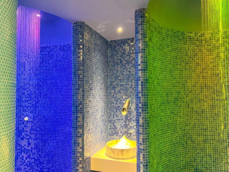 Modern shower area with colorful mosaic tiles and a rainfall showerhead