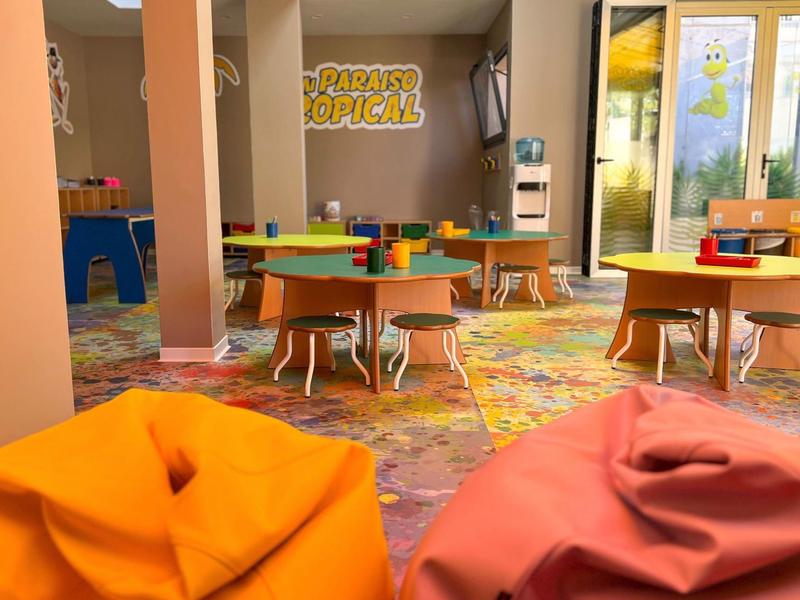 Colorful kids' play area with bean bags, small tables, and toys in a cozy room.