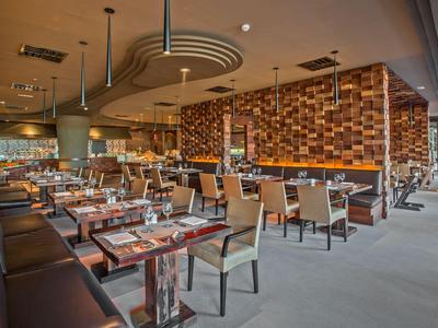 Elegantní restaurace s moderním designem a teplými tóny dřeva a kůže.