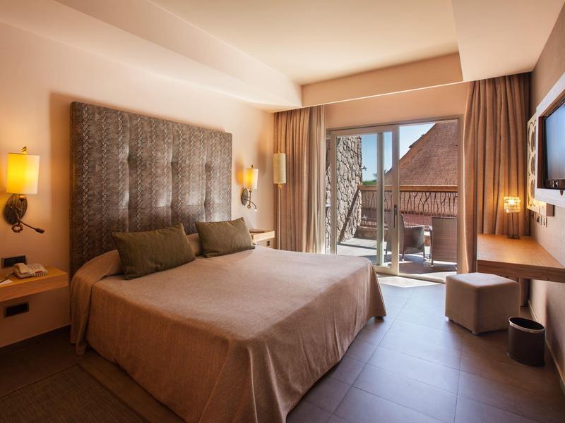 Pokój hotelowy z dużym łóżkiem, nowoczesnym wystrojem i balkonem z widokiem na miasto.