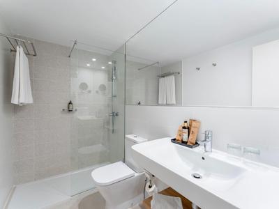 Moderne witte badkamer met glazen douche, grote wastafel en handdoek aan haak.