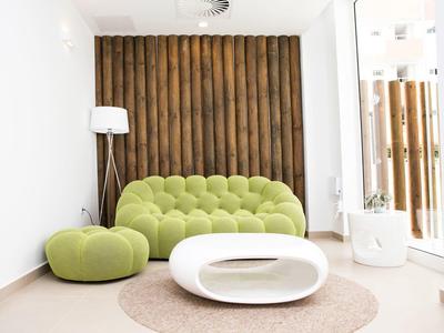 Moderne hotel lobby met groene bank, bijpassende poef, witte salontafel en houten wanddecoratie.