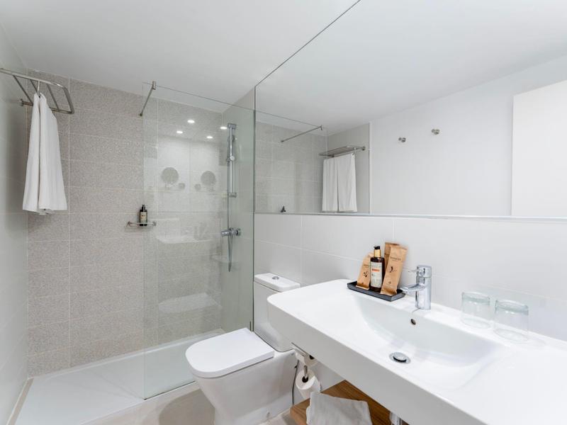 Moderne witte badkamer met glazen douche, grote wastafel en handdoek aan haak.