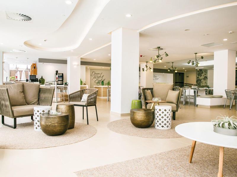 Helere hotelruimte met moderne zitplaatsen, ronde tafels en zachte neutrale tinten.