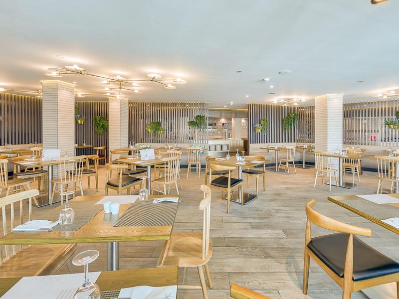 Ristorante luminoso e moderno con pareti bianche, mobili in legno e decorazioni minimaliste.