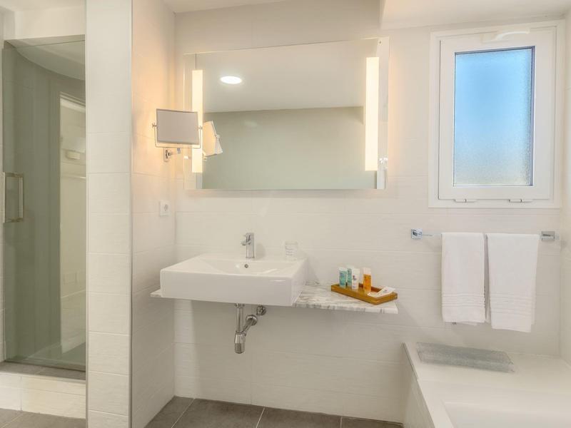 Bagno luminoso e moderno con lavabo, specchio illuminato e cabina doccia.