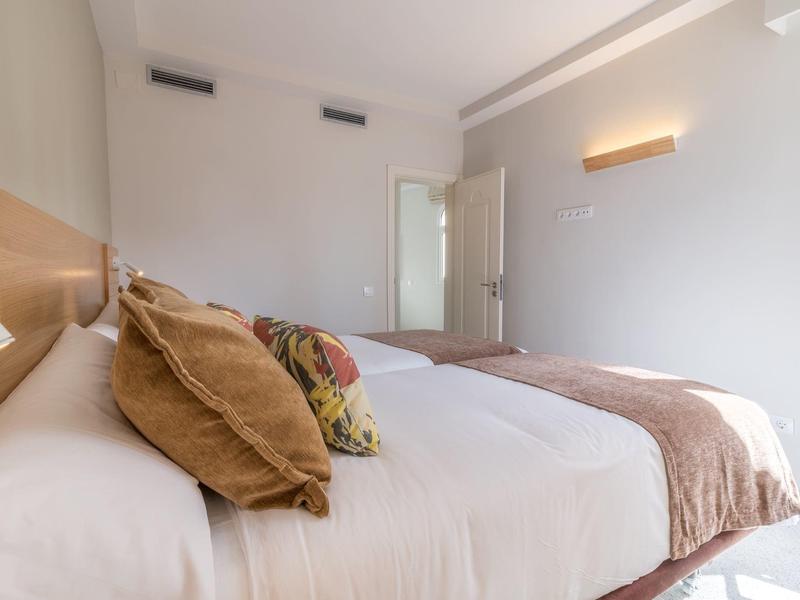 Camera d'hotel luminosa con letto grande, cuscini e coperte morbide.