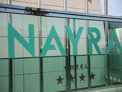 Glasfassade eines Hotels mit grünem Schriftzug 'NAYRA' und drei Sternen.