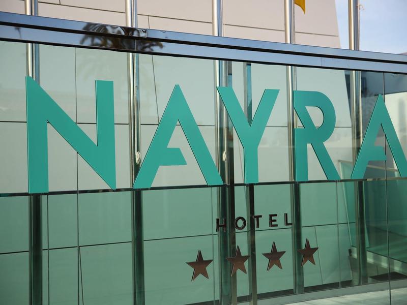 Glasfassade eines Hotels mit grünem Schriftzug 'NAYRA' und drei Sternen.