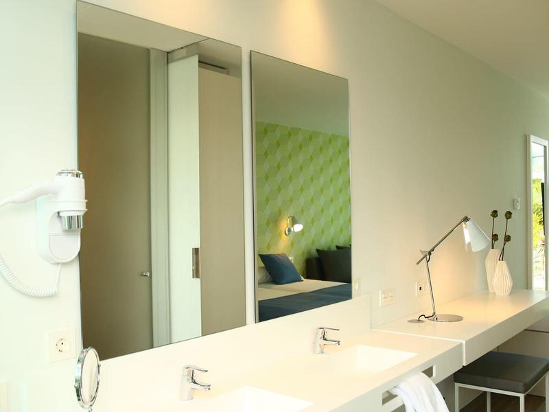 Moderner Waschraum mit großem weißen Waschbecken, Spiegeln und grünem Akzent an der Wand.