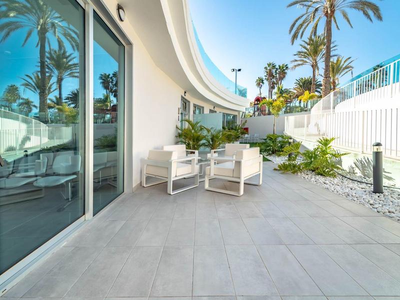 Terrazza con sedie bianche e porte a vetri in un hotel moderno sotto il sole