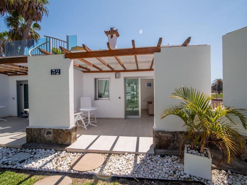Bungalow moderno con terrazza, muri bianchi e sole mediterraneo.