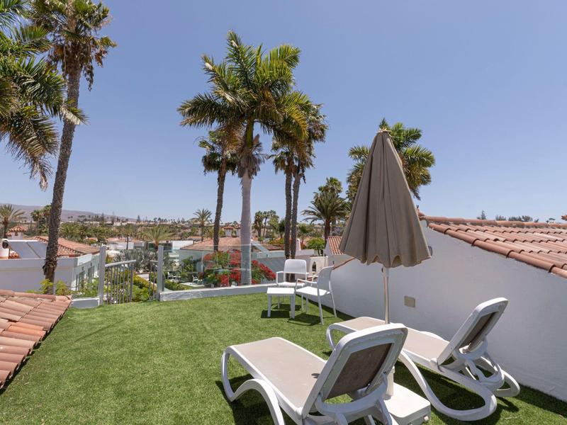Terrazza con lettini, prato artificiale verde e vista mare sotto un cielo sereno