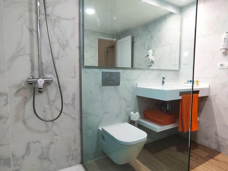 Nowoczesna łazienka hotelowa z prysznicem, toaletą, umywalką i dużymi lustrami