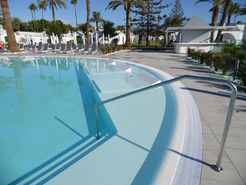 Pusty basen hotelowy z poręczą i leżakami pod czystym niebem.