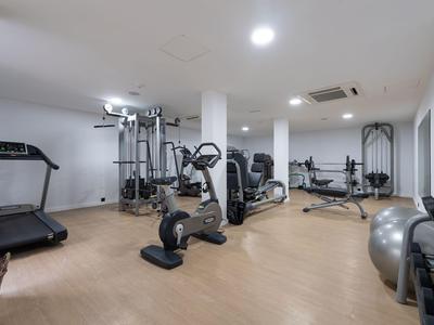 Moderní posilovna s různými cvičebními stroji a světlými stěnami a podlahou