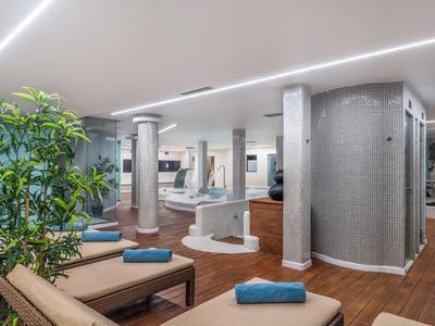 Moderner Wellnessraum mit Liegen, grünen Pflanzen und gedämpftem Licht.