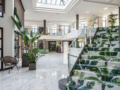 Helles, modernes Treppenhaus mit großen Pflanzenmustern auf den Stufen und Glasgeländer.