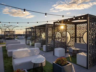 Dachterrasse mit Sitzmöbeln aus Rattan, hängenden Lichtern und dekorativen Trennwänden bei Sonnenuntergang.