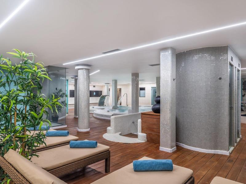 Moderner Wellnessraum mit Liegen, grünen Pflanzen und gedämpftem Licht.