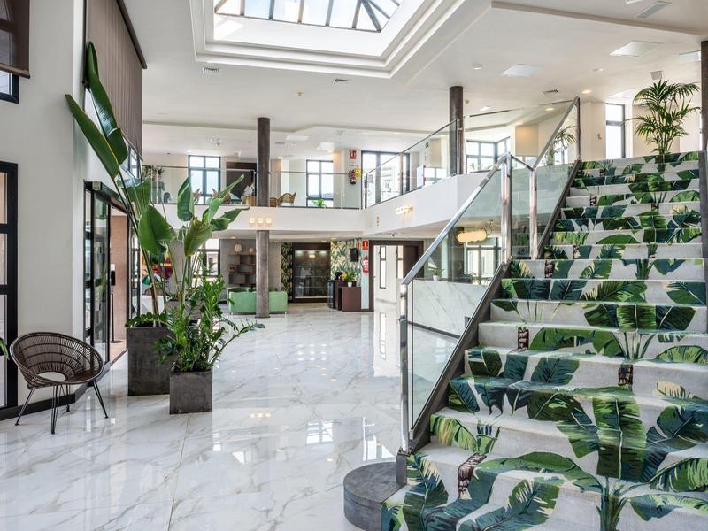 Helles, modernes Treppenhaus mit großen Pflanzenmustern auf den Stufen und Glasgeländer.