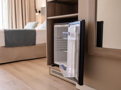 Piccolo mini frigorifero da hotel con porta aperta in una camera moderna.