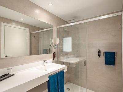 Bagno moderno con grande specchio, lavandino bianco e cabina doccia in vetro.