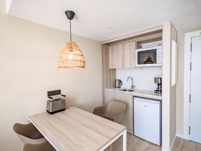 Piccola angolo cottura con tavolo, due sedie e lampada in legno in una camera d'hotel.