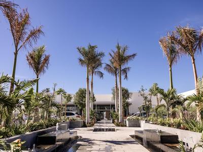 Nowoczesny teren zewnętrzny z palmami i bujną zielenią w słoneczny dzień.