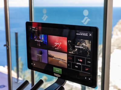 Ekran wyświetlający różne treści wideo przed oknem z widokiem na morze