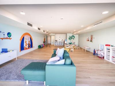 Ampia stanza comune moderna e luminosa con divani, tavolo per bambini e decorazioni murali.