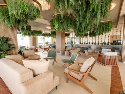 Area lounge moderna in hotel con piante sospese e comodi posti a sedere.