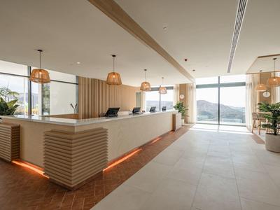 Reception dell'hotel moderna con dettagli in legno, ampie finestre e vista panoramica sulle montagne.