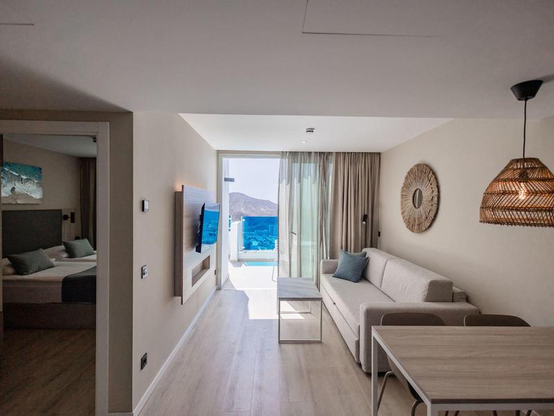 Soggiorno luminoso con mobili moderni, vista attraverso la finestra sull'area esterna dell'hotel.