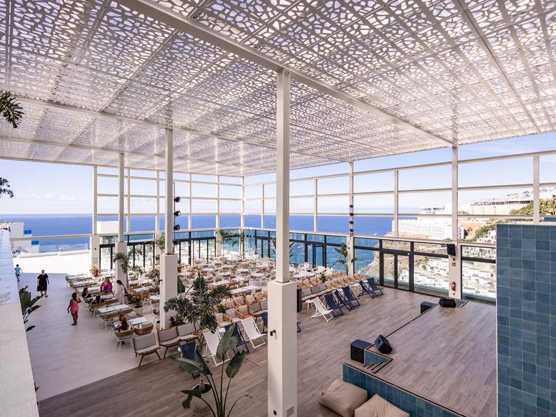 Lounge aperta con vista sul mare e tetto in materiale traforato che offre ombra parziale.