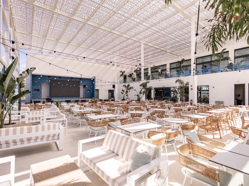 Ristorante luminoso e moderno con mobili bianchi e in legno e molta luce naturale.