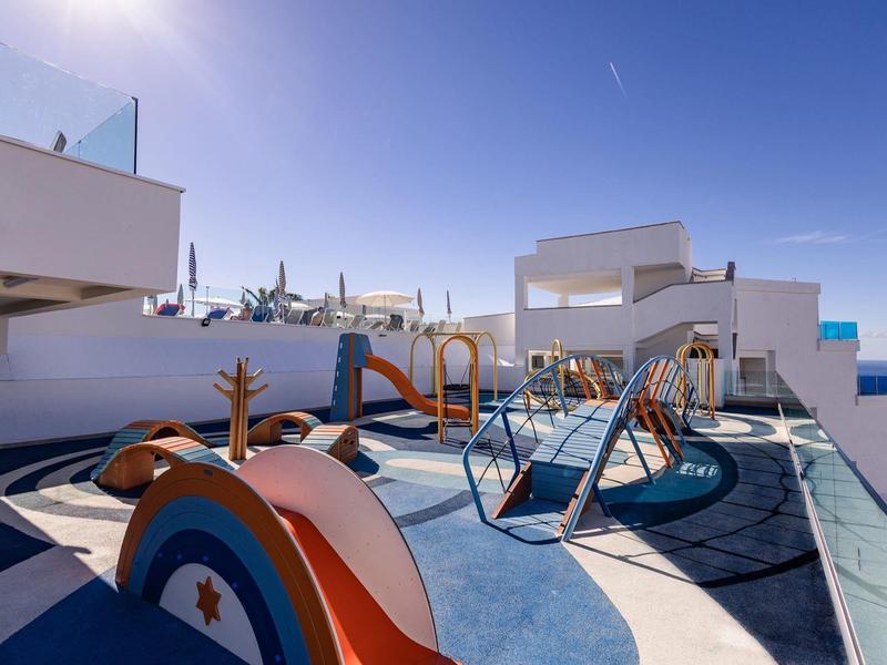 Moderno parco giochi per bambini su un tetto di hotel soleggiato con cielo blu