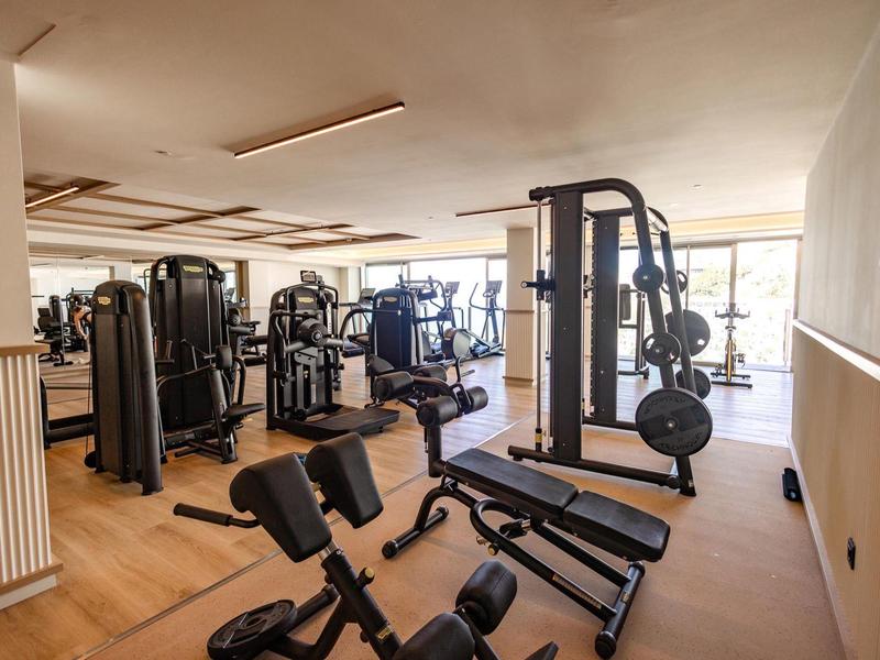 Palestra luminosa con diverse attrezzature e ampie finestre per luce naturale.