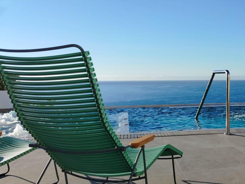 Sdraio verde a bordo piscina con vista sul mare e cielo limpido.