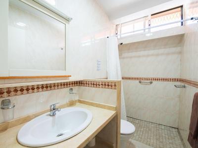 Kleines Badezimmer mit Waschbecken, Spiegel, Handtuchhalter und ebenerdiger Dusche mit Glaswand.