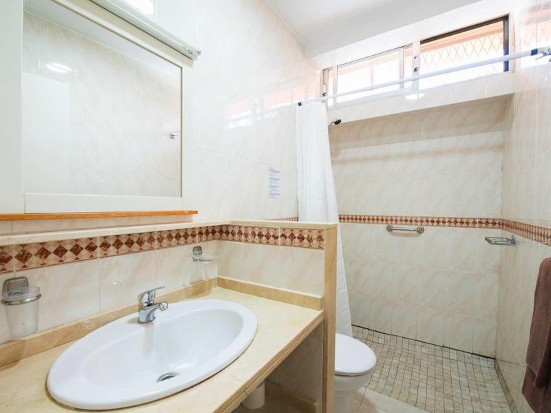 Lichte badkamer met wastafel, spiegel, inloopdouche en beige betegelde muren.