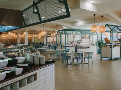 Salle à manger moderne et lumineuse avec cuisines ouvertes et plusieurs places assises.
