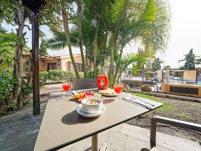 Tavolo in terrazza con bevande e cibo davanti a un giardino tropicale in hotel