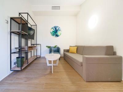 Salon moderne avec canapé marron, table basse blanche et étagère en bois au mur.
