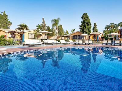 Czysty basen z leżakami i bungalowes pod niebieskim niebem