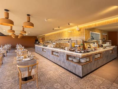 Elegante restaurante de hotel con buffet, muebles de madera y luz cálida.