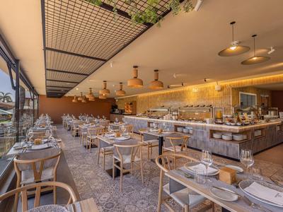 Restaurante moderno con muebles de madera y área de buffet en un hotel luminoso.