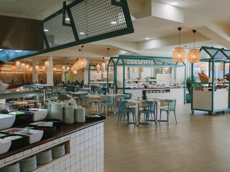 Salle à manger moderne et lumineuse avec cuisines ouvertes et plusieurs places assises.