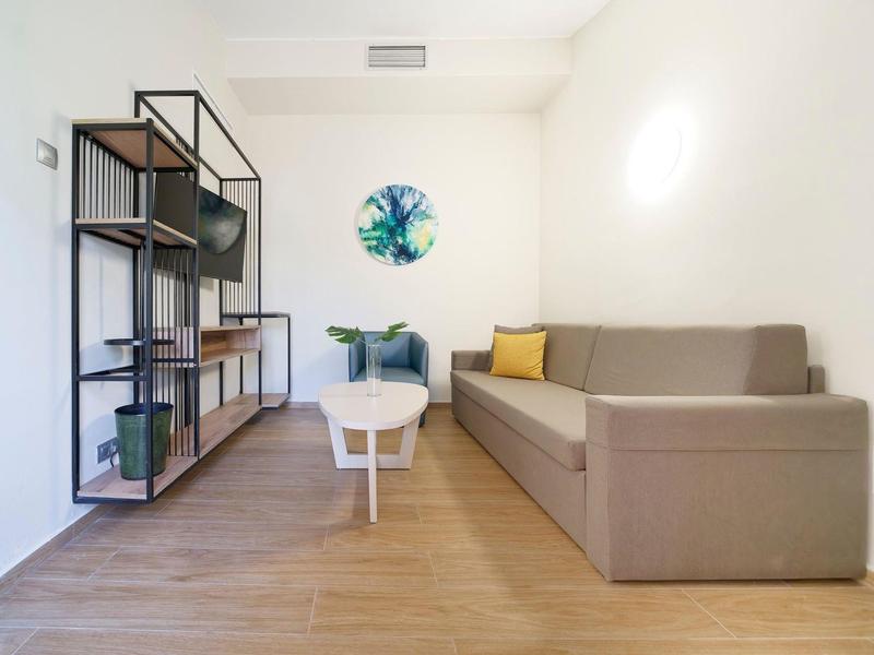 Salon moderne avec canapé marron, table basse blanche et étagère en bois au mur.