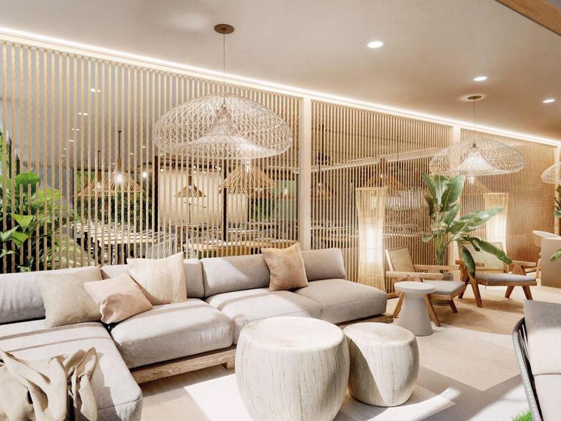 Salon d'hôtel lumineux et moderne avec canapés confortables, tabourets ronds et plantes.